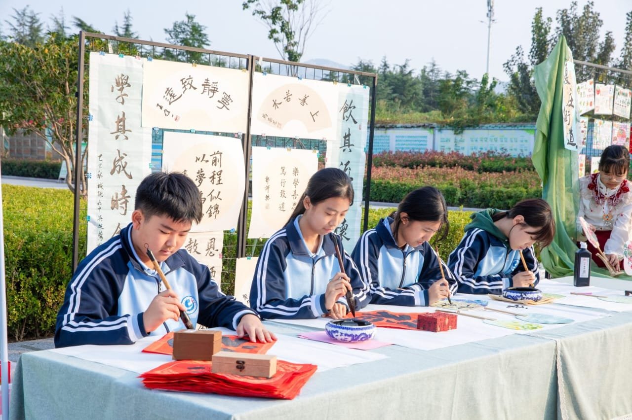 Jóvenes estudiantes practicando caligrafía tradicional china con pincel y tinta al aire libre.